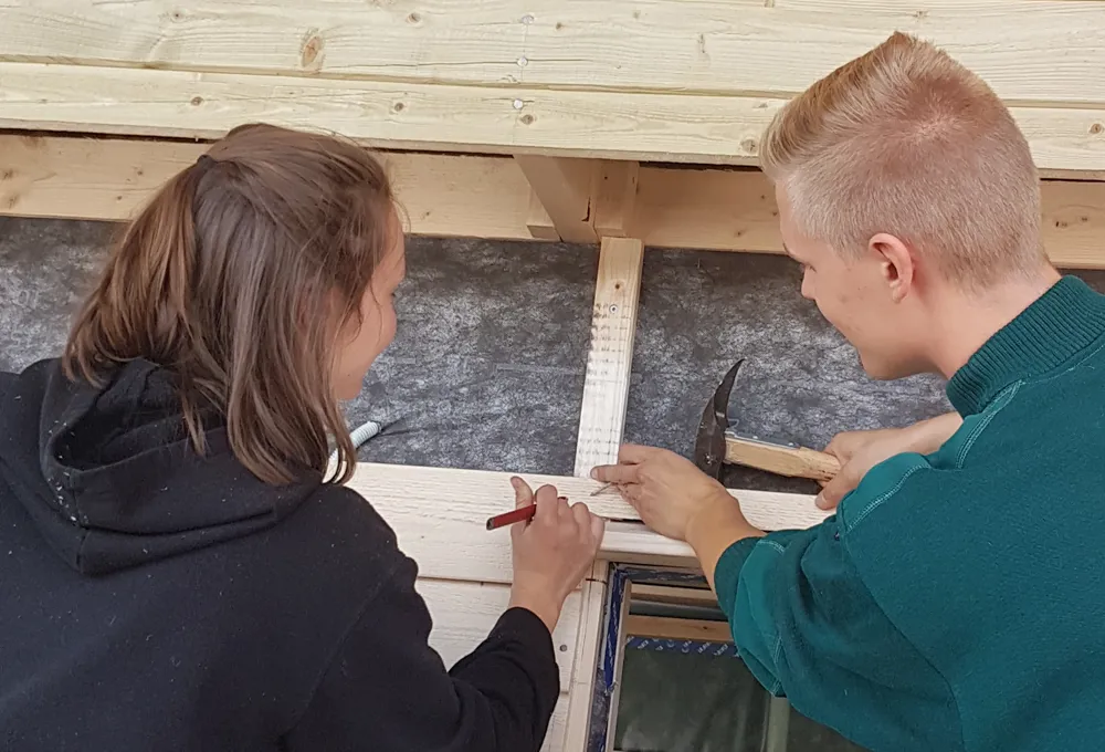 Pige og dreng på tømreruddannelsen samarbejder