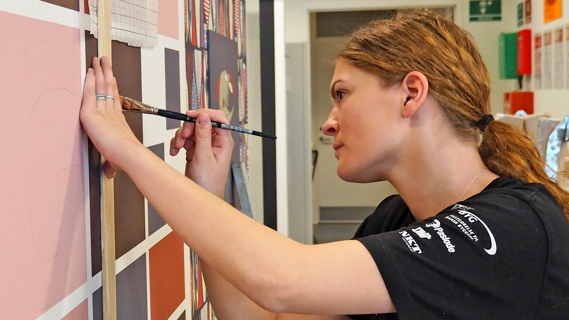 Kvindelig bygningsmaler maler vægdekoration med bogstaver