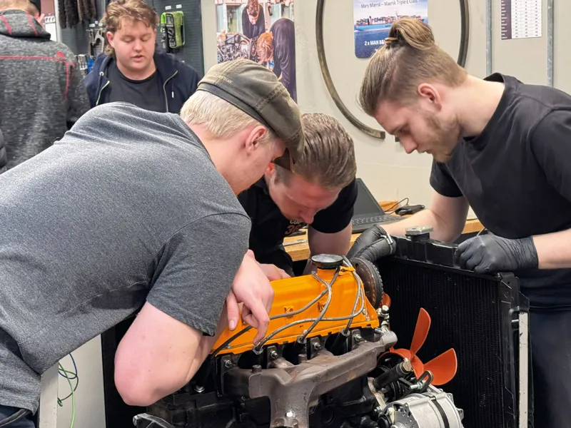 Tre drenge arbejder på motor