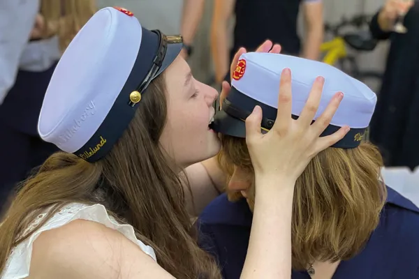 To HTX piger med studenterhuer - den ene pige bider i skyggen på den andens hue