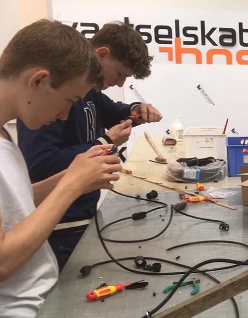 Gruppe af elektrikere sidder ved et bord og sammensætter ledninger