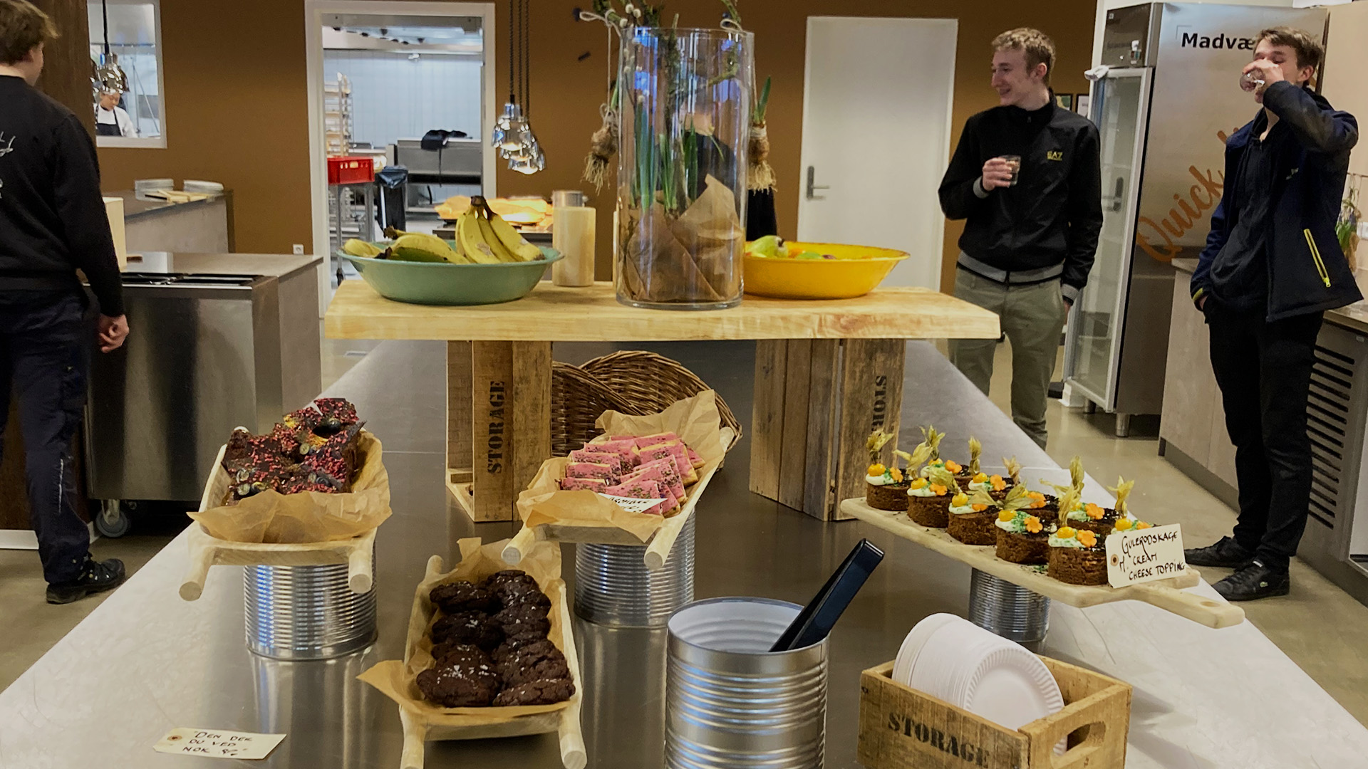 Stort udvalg af kage i Madværket, med elever i baggrunden