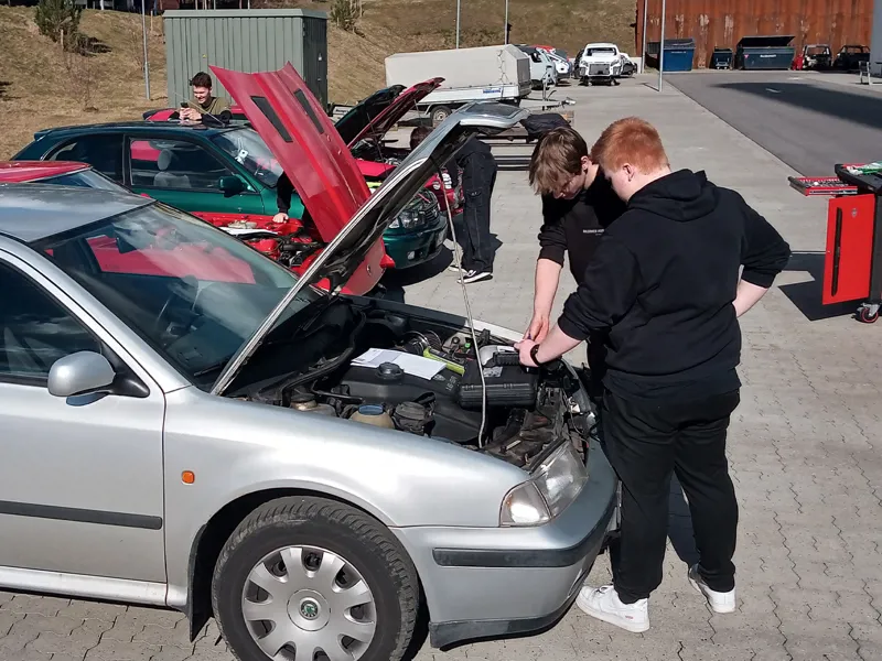 Elever på mekanikeruddannelsen laver reparationer på biler udendørs