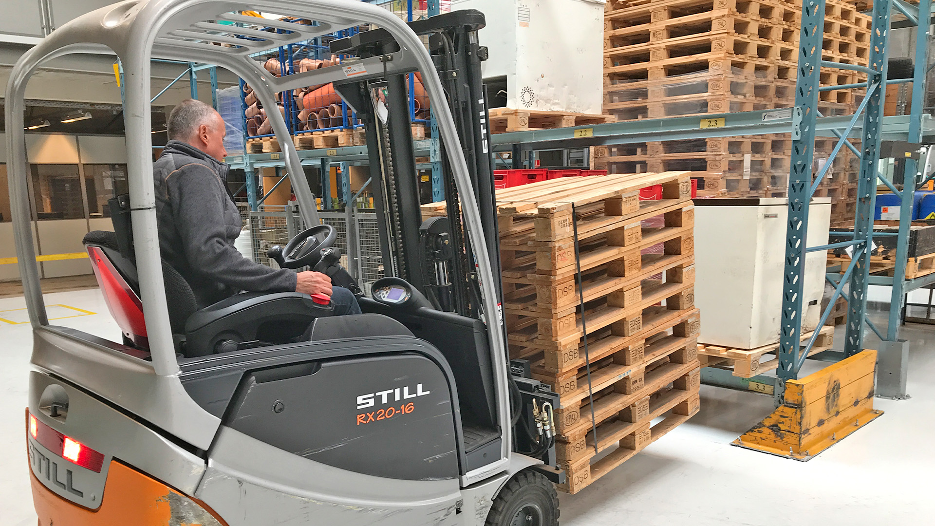 Truckfører sætter stak med paller på plads i lagerreol under AMU kursus på College360