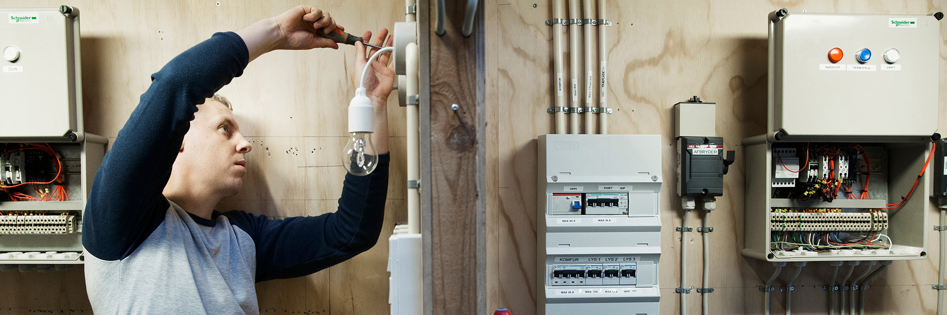 Elektriker arbejder i kabine med elinstallation 