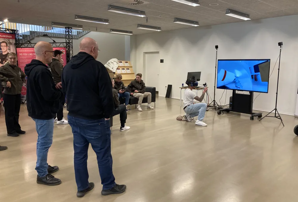 Mennesker kigger på mens elev afprøver laksimulator