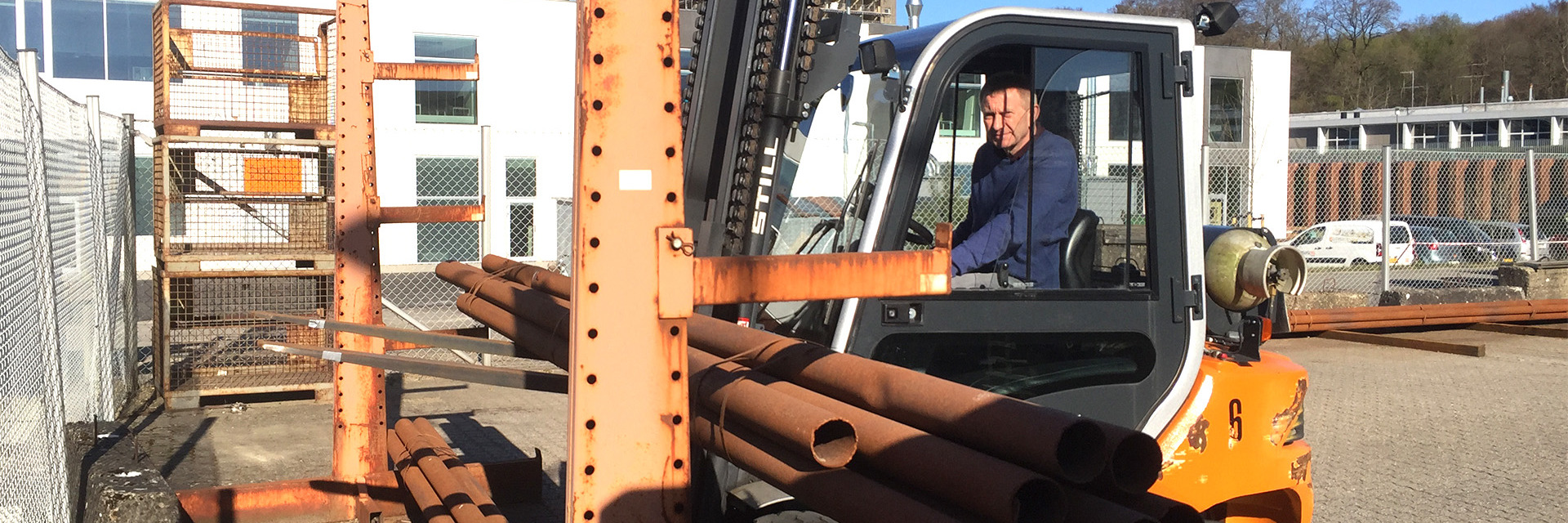 Truckfører løfter jernrør under truckundervisning på College360