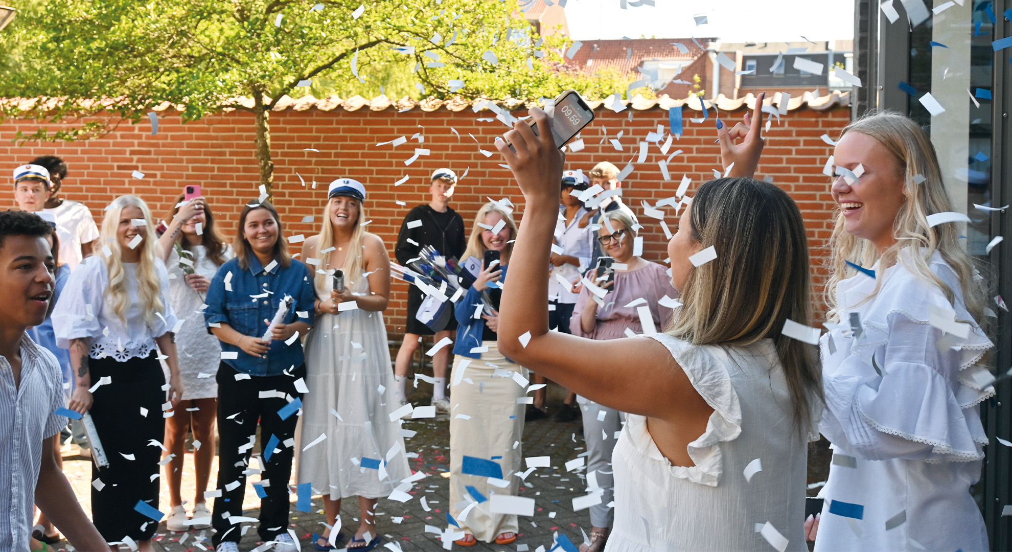 Pige kommer ud fra sidste eksamen og fejres af venner og familie med konfetti, før huen sættes på